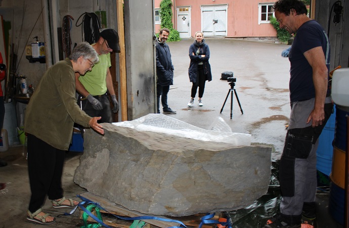 Tre personer pakker ut en stor stein. 