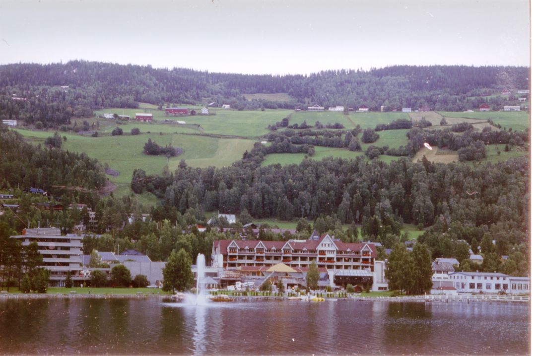En rekke smågårder i en slak helling ned mot et vann, hvor det er et stort hotellkompleks . 