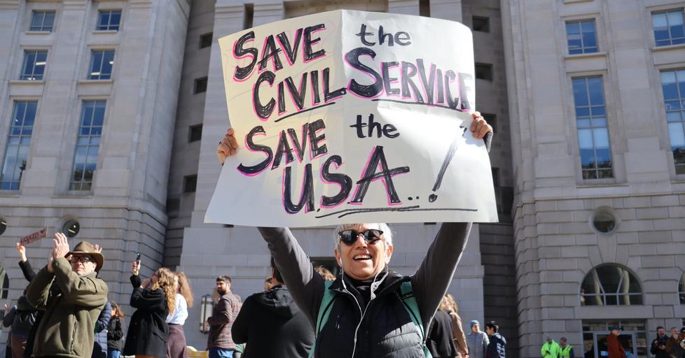 Protester holding up a sign with the text "Save the civil servise, save the USA"