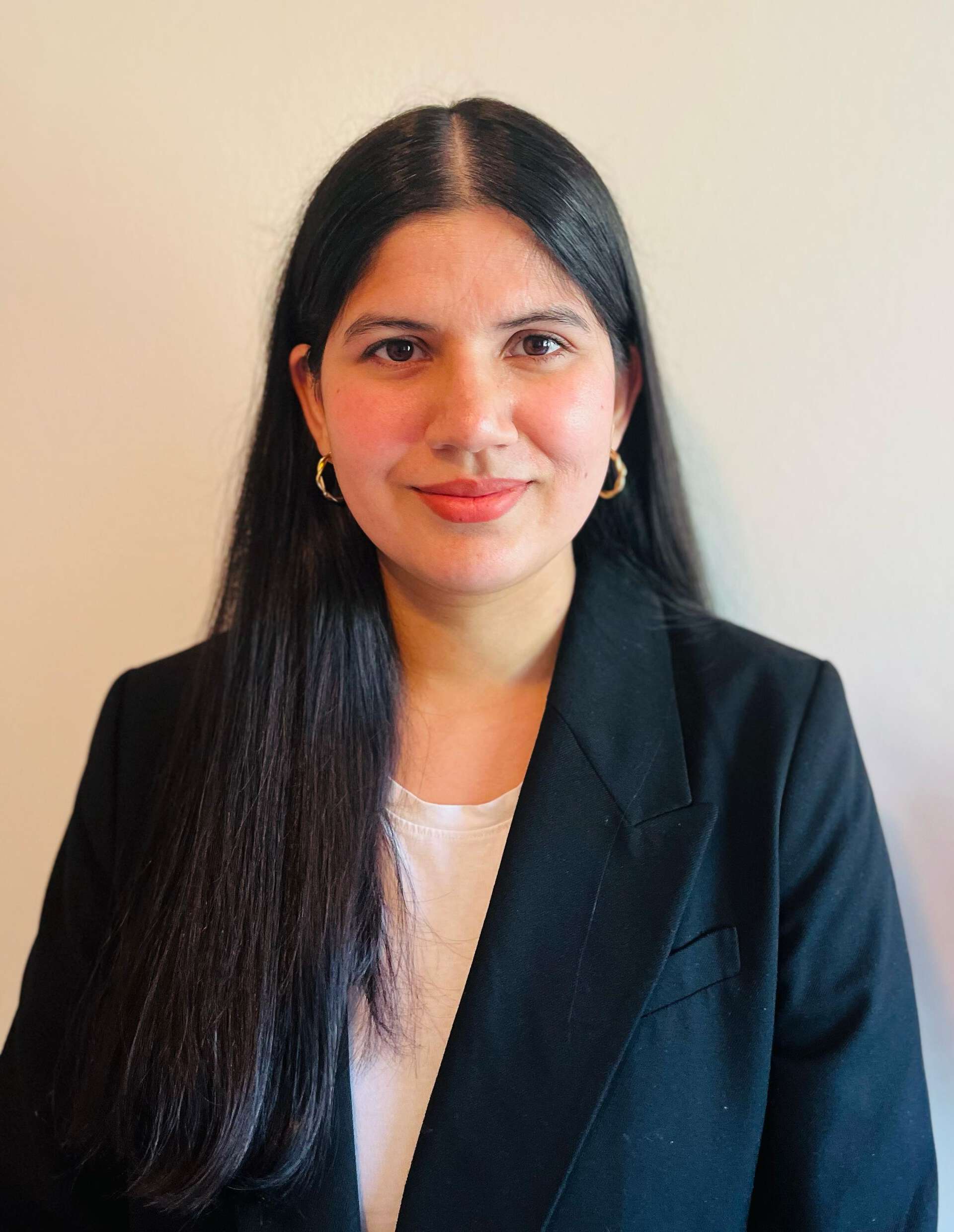 Vice President Zeenat smiling professionally in front of a beige background.