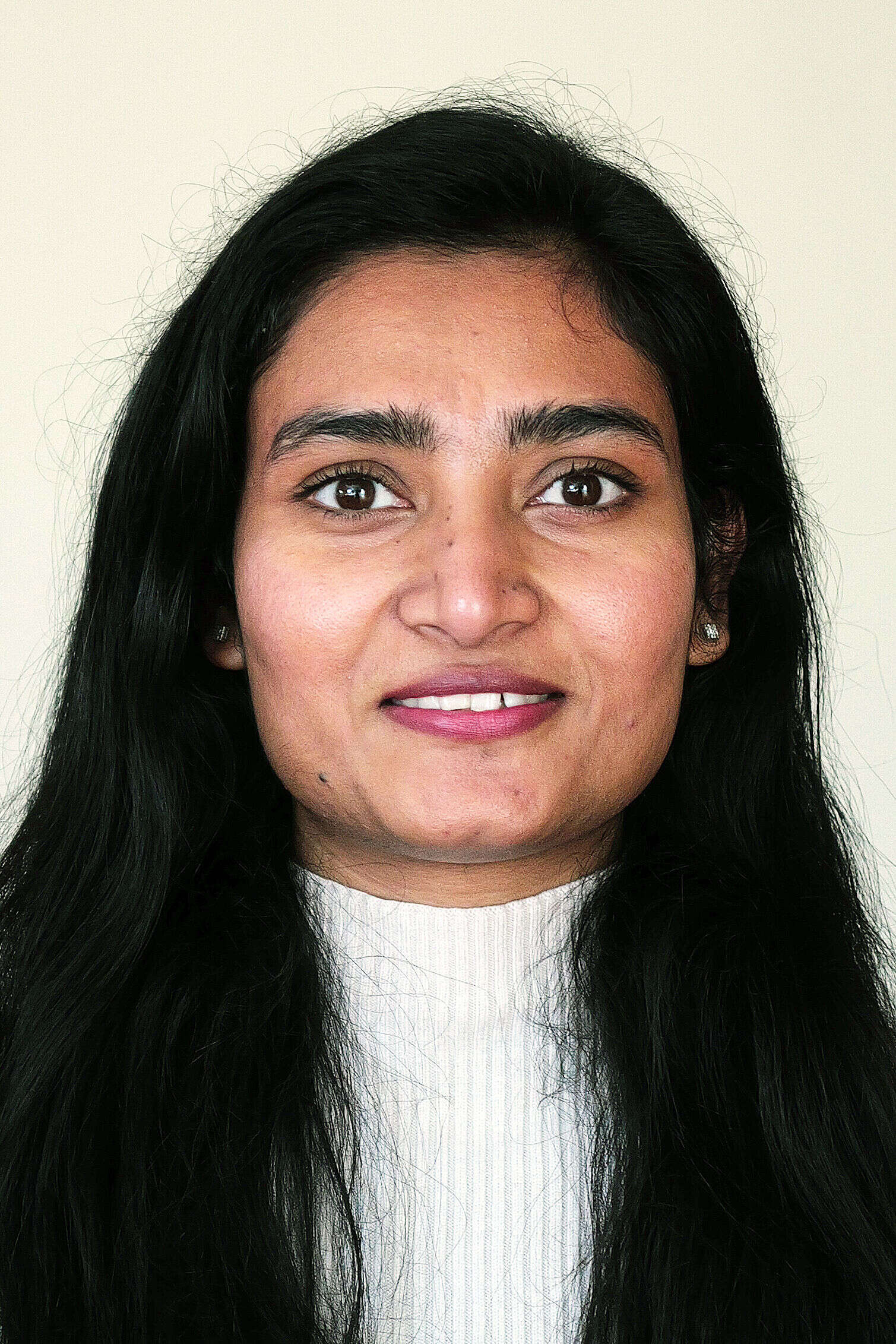 Event Officer Pooja is smiling professionally in front of a beige background.