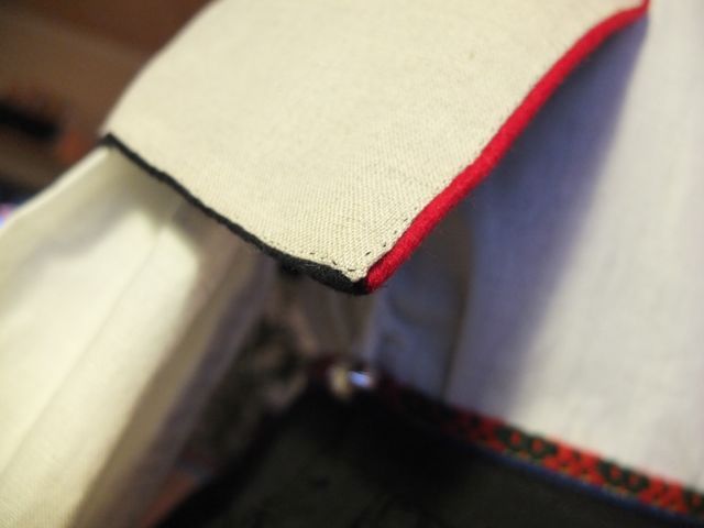Det røde kantebåndet er brettet i nedre kant. Forstykket er brettet rundt og foret er sydd fast i begge.