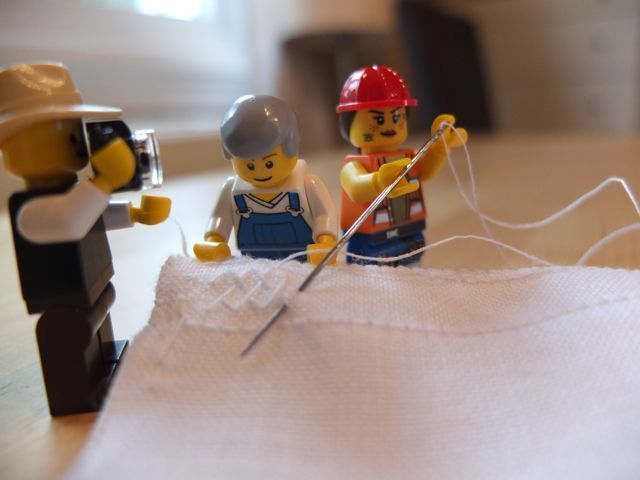 Legofigurer som holder stoff og syr. En legofotograf dokumenterer.